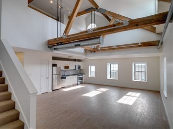 An open living room with a kitchen and exposed beams in the ceiling