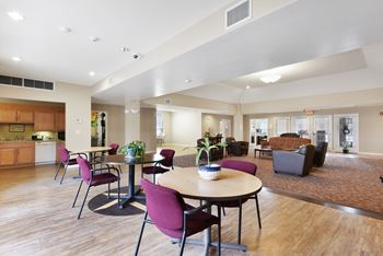 A resident clubhouse with tables chairs and a kitchen in the background