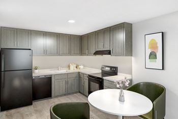 A modern kitchen with a black refrigerator and grey cabinets