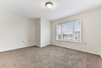 A bedroom with a large window and carpet