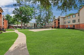 Spring apartment for rent - A grassy area with a concrete walkway and apartment buildings in the background.