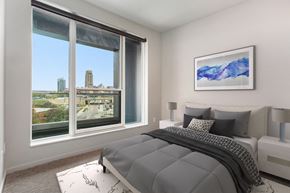 Grand Rapids apartment for rent - a bedroom with a bed and a large window with a city view