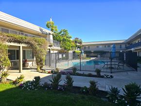 Anaheim apartment for rent - A pool surrounded by a black fence and a green lawn.