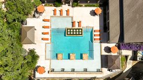 San Antonio apartment for rent - An aerial view of a pool surrounded by orange chairs and green plants.