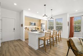 San Antonio apartment for rent - A kitchen with wooden floors and a white island with chairs around it.
