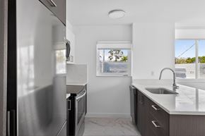 Miami Beach apartment for rent - A modern kitchen with a stainless steel refrigerator and a window overlooking a tree-lined street.