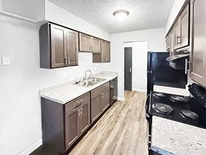 Battle Creek apartment for rent - A kitchen with dark brown cabinets and a black stove top oven.
