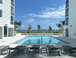 Miami townhouse for rent - an outdoor pool with lounge chairs and a view of the Miami skyline  at Douglas Enclave, Miami, FL, 33125