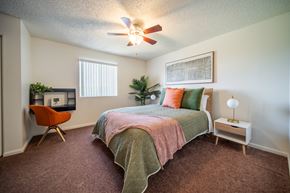 Flagstaff apartment for rent - A bedroom with a bed, chair, and plants.