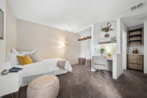Flagstaff apartment for rent - A bedroom with a white bed and a grey chair.