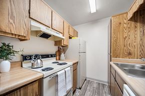 Tucson apartment for rent - A kitchen with wooden cabinets and a white stove top oven.