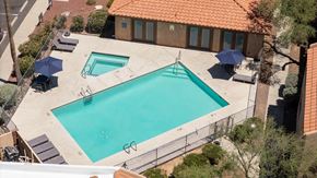 Tucson apartment for rent - An outdoor swimming pool surrounded by a fence and trees.