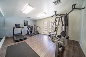 Tucson apartment for rent - A well-equipped home gym with a treadmill, elliptical machines, and a weight bench.