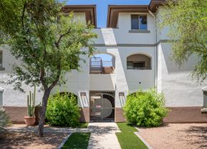Tucson apartment for rent - A white building with a gate in the middle of a landscaped yard.