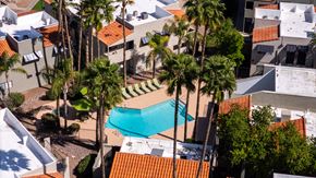 Tucson apartment for rent - A swimming pool surrounded by palm trees and buildings.
