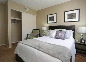 Tucson apartment for rent - A bedroom with a large bed and a green chair.