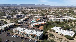 Tucson apartment for rent - A large apartment complex is surrounded by a parking lot and other buildings.