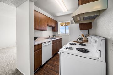 Tucson apartment for rent - A white stove top oven with four burners is in a kitchen with wooden cabinets.