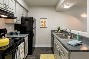 Tucson apartment for rent - a kitchen with white cabinetry and black appliances