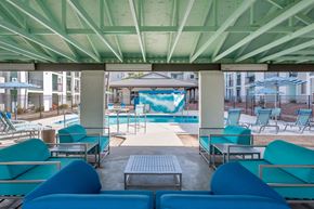 Tucson apartment for rent - a lounge area with blue couches and chairs and a pool in the background