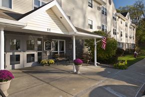 Troy apartment for rent - the front of a white building with a porch and an flag