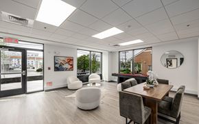 West Hartford apartment for rent - A modern office space with a wooden table and chairs, a white bean bag, and a view of the city through the windows.