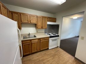 Guilderland apartment for rent - an empty kitchen with wooden cabinets and a white stove and refrigerator