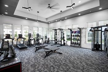 A spacious fitness room with cardio equipment and windows