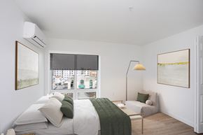 West Hartford apartment for rent - A bedroom with a bed, a couch, and a window with a view of the city.