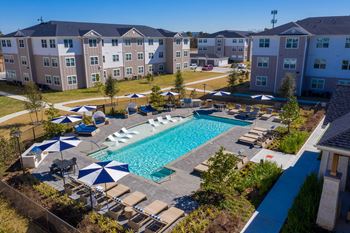 An aerial view of the resort style pool with chaise lounge chairs and umbrellas