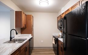 Mechanicville apartment for rent - A kitchen with a black refrigerator and wooden cabinets at Hudson Heights Apartments, Mechanicville, NY