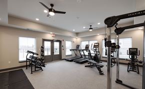 Mechanicville apartment for rent - A gym with a variety of equipment including a treadmill, weights, and a squat rack at Hudson Heights Apartments, Mechanicville, NY