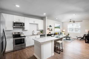 Houston apartment for rent - a kitchen and living room with white cabinets and stainless steel appliances at 55 Fifty at Northwest Crossing, Houston Texas