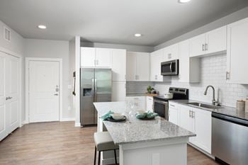 A white kitchen with a granite counter top and stainless steel appliances