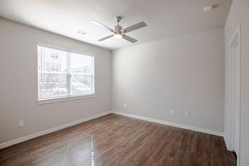 A bedroom with a ceiling fan and a window