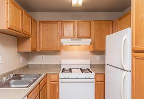 Mcallen apartment for rent - a kitchen with white appliances and wooden cabinets