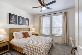 Katy apartment for rent - A bedroom with a bed, a ceiling fan, and a chair.