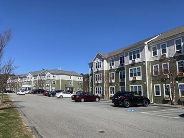 Barnstable apartment for rent - A parking lot with cars and apartment buildings in the background.