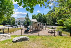 Tyngsborough apartment for rent - A playground with a slide and a wooden structure surrounded by a fence.