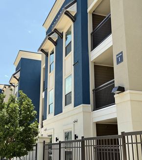 Houston apartment for rent - A blue and white building with a black gate in front.