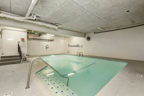 Seattle apartment for rent - an indoor swimming pool in a building with white walls and concrete floors