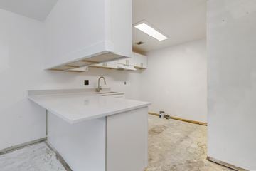 Seattle apartment for rent - the kitchen is being remodeled with white cabinets and white counter tops and a sink