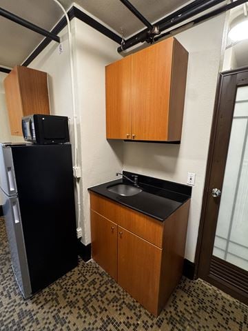 Seattle apartment for rent - A small kitchen with a black fridge and a black counter top.