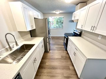 University Place apartment for rent - A kitchen with white cabinets and a wooden floor.