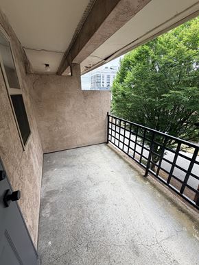 Seattle apartment for rent - A balcony with a black railing and a view of a building and trees.