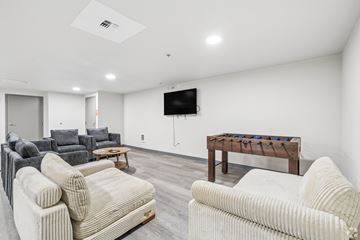 Seattle apartment for rent - A living room with a white couch, grey couch, and a wooden table with a TV mounted on the wall.