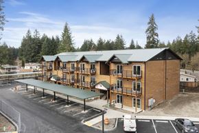 Lacey apartment for rent - A large building with a green roof and a parking lot in front.