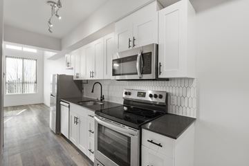 Seattle apartment for rent - A modern kitchen with white cabinets and black countertops.