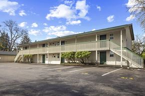 Lakewood apartment for rent - A building with a green roof and a parking lot in front.
