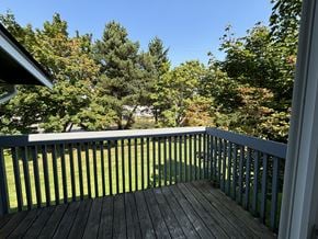 Tacoma apartment for rent - A wooden deck with a railing overlooking a grassy area.